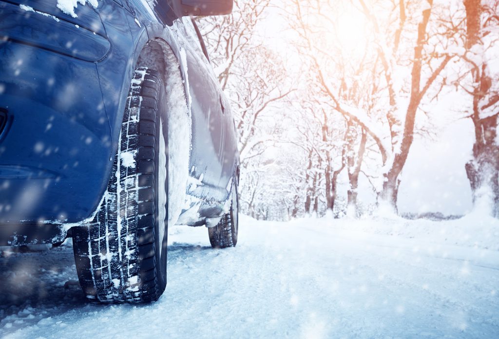 Car tires on winter road covered with snow. Vehicle on snowy alley in the morning at snowfall